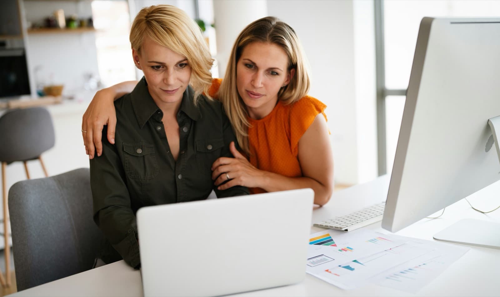 A parent with an arm around a young adult as they look at a laptop together